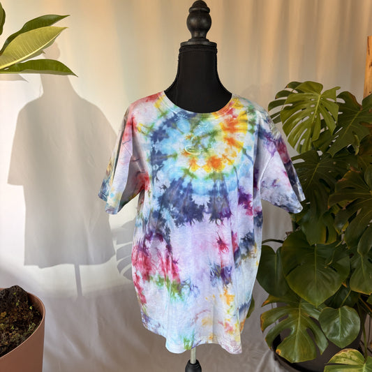 Multicolored tie-dye t-shirt on a mannequin with plants in the background