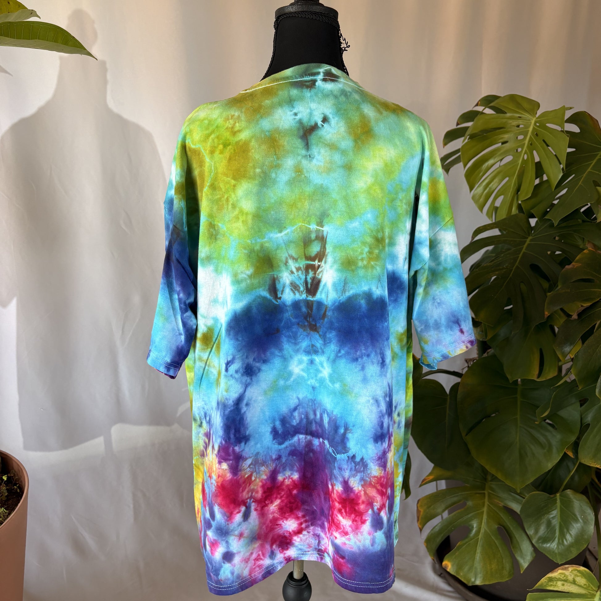 Colorful tie-dye shirt on a mannequin with plants in the background