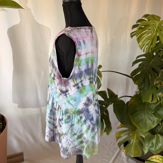 Multicolored tie-dye flowy tank top on a mannequin with plants in the background