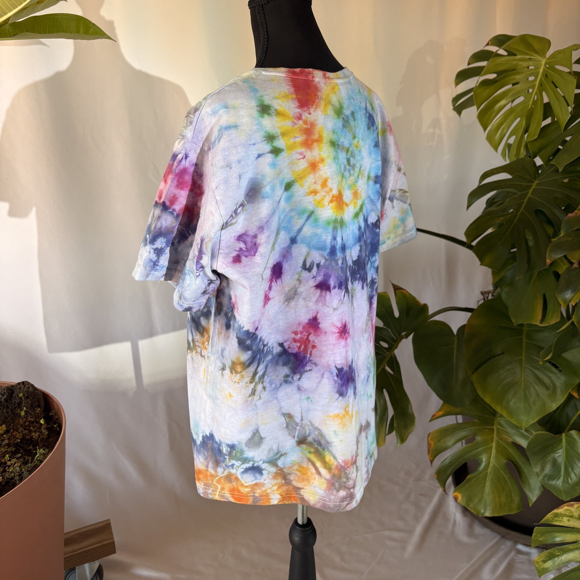 Colorful tie-dye shirt on a mannequin with plants in the background