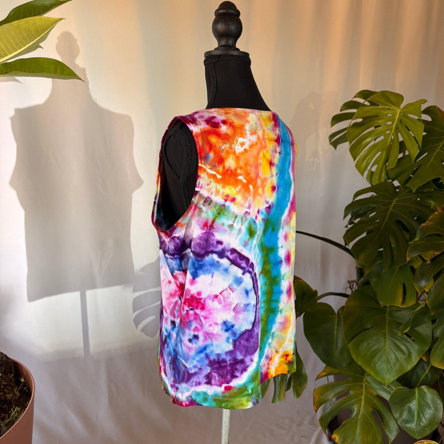 Colorful tie-dye tank top on a mannequin with plants in the background