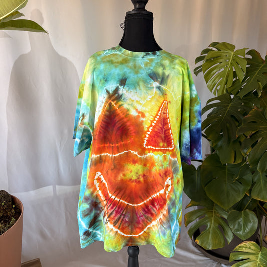Colorful jack-o-lantern tie-dye shirt on a mannequin with plants in the background